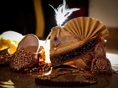A detailed view of luxurious Indian groom accessories featuring an ornate turban and embellished shoes indoors.